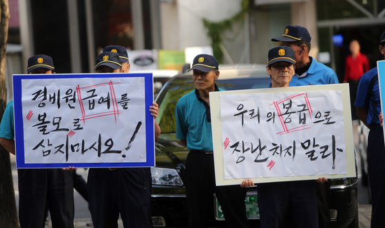 9월 15일 대전의 한 아파트 입구에서 이 아파트 경비원과 청소노동자, 시설관리직 관계자들이 '우리의 급여를 볼모 삼지 말라'는 피켓 시위를 하고 있다. [연합뉴스]