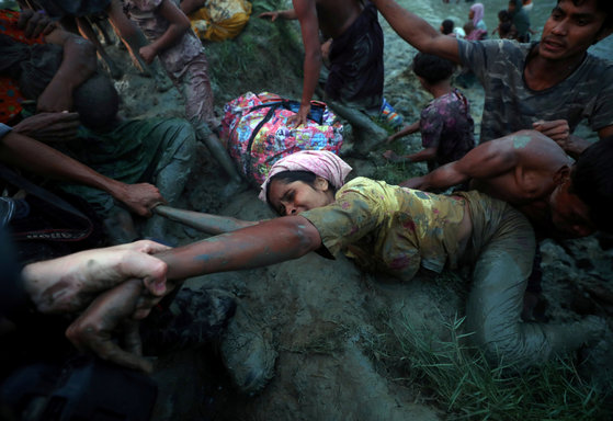 11월 1일. 미얀마의 '인종 청소'를 피해 강을 넘어 방글라데시로 탈출하고 있는 로힝야 여성의 손을 잡고 도와주는 사진기자. [REUTERS=연합뉴스/Hannah McKay]