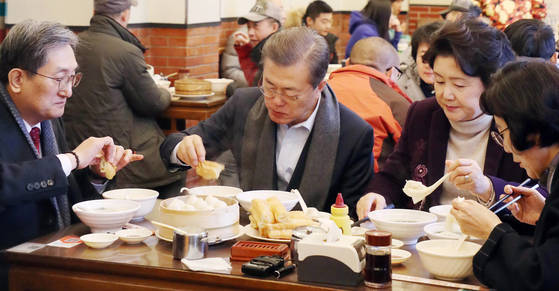 문재인 대통령과 부인 김정숙 여사가 지난 14일 오전 중국 베이징 조어대 인근 한 현지 식당에서 중국인들이 즐겨 먹는 아침 메뉴인 만두(샤오롱바오), 만둣국(훈둔), 꽈배기(요우티아오), 두유(도우지앙)을 주문해 식사를 하고 있다.   유탸오는 밀가루를 막대 모양으로 빚어 기름에 튀긴 꽈배기 모양의 빵으로 겉은 바삭하고 속은 말랑한 식감이 특징이다. 중국식 두유인 더우장에 적셔서 먹는 중국 일반 시민의 대표적인 아침 식사다. 왼쪽은 노영민 주중 한국대사. [연합뉴스]