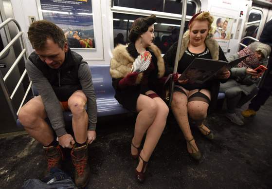 미국 뉴욕의 지하철에서 한 남성(왼쪽)이 '바지 벗고 지하철 타기' 행사에 동참하기 위해 바지를 벗고 있다. 오른쪽은 행사에 참여한 승객.[AFP=연합뉴스]