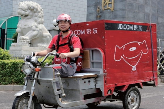 중국 전자상거래 회사 JD.com의 설립자 리처드 리우가 2014년 6월 16일 회사 창립 기념일 축하의 일환으로 전기 삼륜 오토바이를 타고 배달에 나섰다.