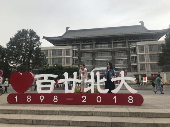 5일 중국 베이징대 도서관 앞에 세워진 개교 120주년 기념 엠블럼에서 졸업생과 자녀가 기념 사진을 촬영하고 있다. [사진=신경진 기자]