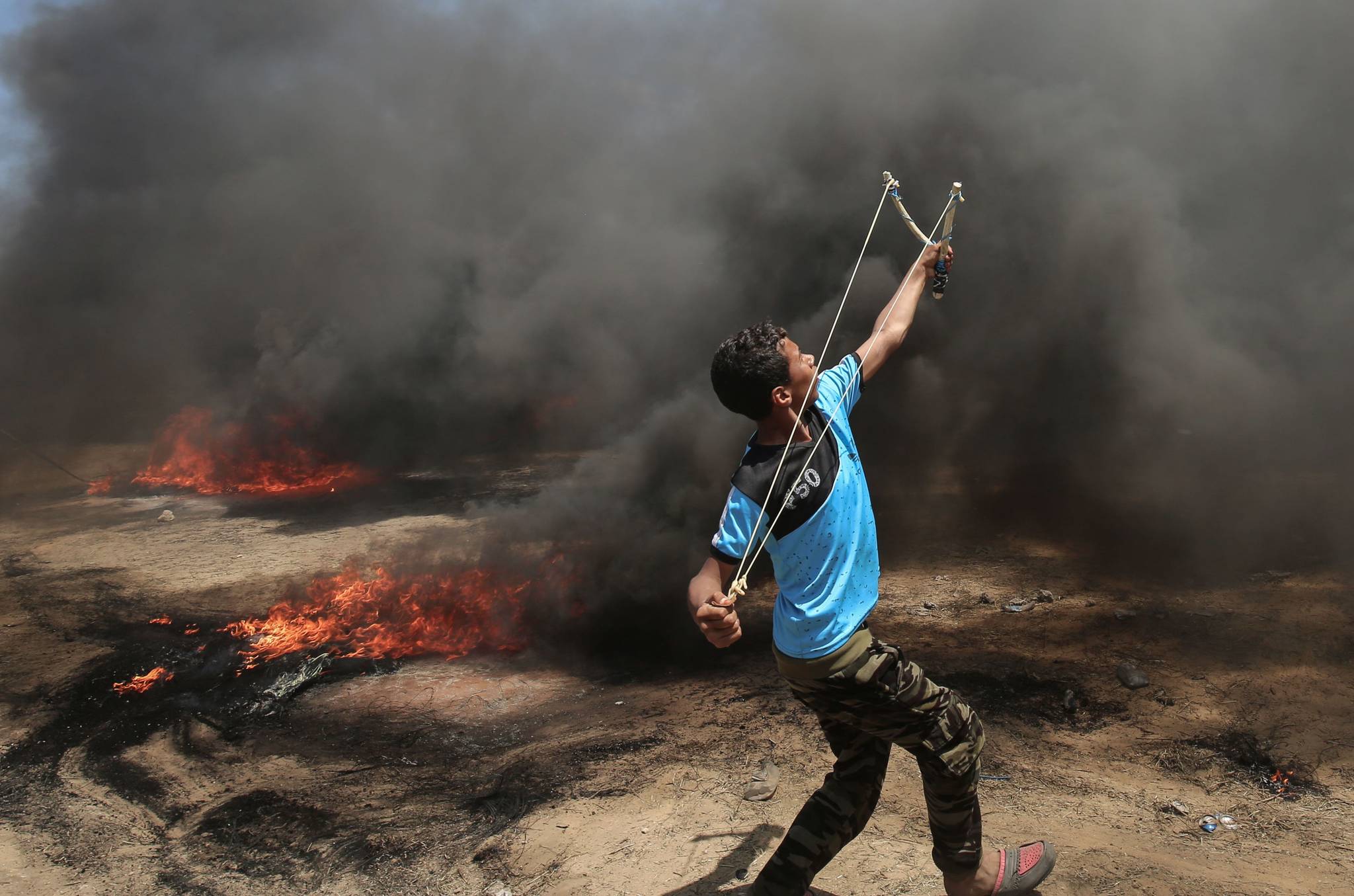  한 팔레스타인 청년이 14일 가자지구에서 이스라엘로 향해 새총을 쏘고 있다. [AFP=연합뉴스]
