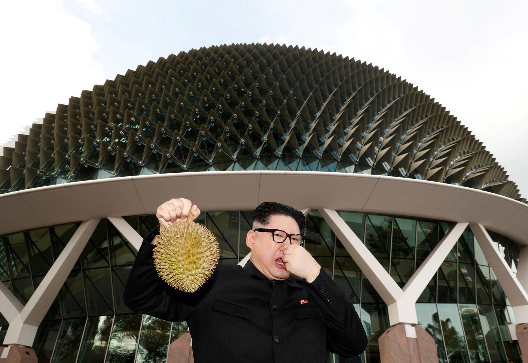 가짜 김정은이 열대과일 두리안을 닮은 싱가포르 관광지인 에스플러네이드 앞에서 두리안을 들고 코를 막고 있다. [로이터=연합뉴스]