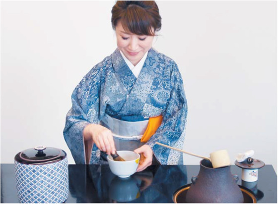 말차를 대나무 막대로 저어 거품을 내는 일본 여성.