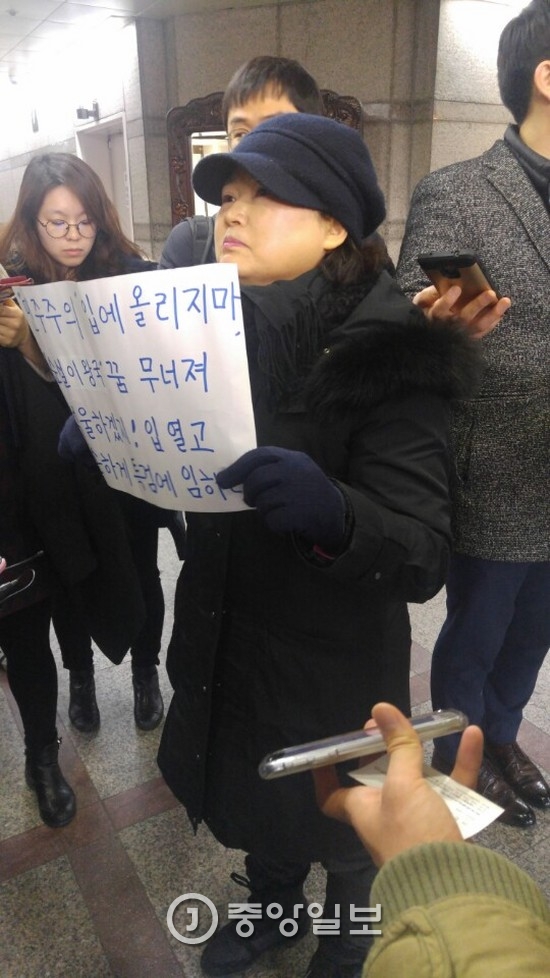 한 시민이 최순실씨를 비판하는 글이 적힌 종이를 들고 이경재 변호사 사무실 앞에서 시위를 하고 있다. 김나한 기자