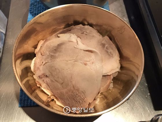 토렴하려고 놋그릇에 밥을 담고 수육 여러 장을 올린 돼지곰탕 한 그릇. 수육은 얇기도 하지만 단면이 깔끔하다. 이렇게 자르기 위해 24시간 냉장해 고깃덩어리를 굳혀야 한다.