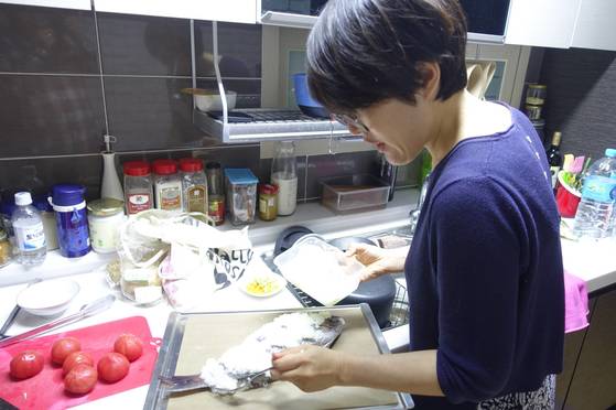 자신의 살림집 주방에서 계란 흰자에 반죽한 굵은 소금을 참돔 몸통에 바르고 있는 김현정 셰프.