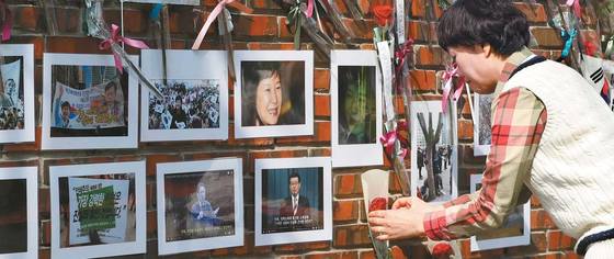 18일 서울 강남구 삼성동 박근혜 전 대통령 자택을 찾은 한 지지자가 ‘통곡의 벽’이라 불리는 자택 담장에 꽃과 응원 문구를 붙이고 있다. 장진영 기자
