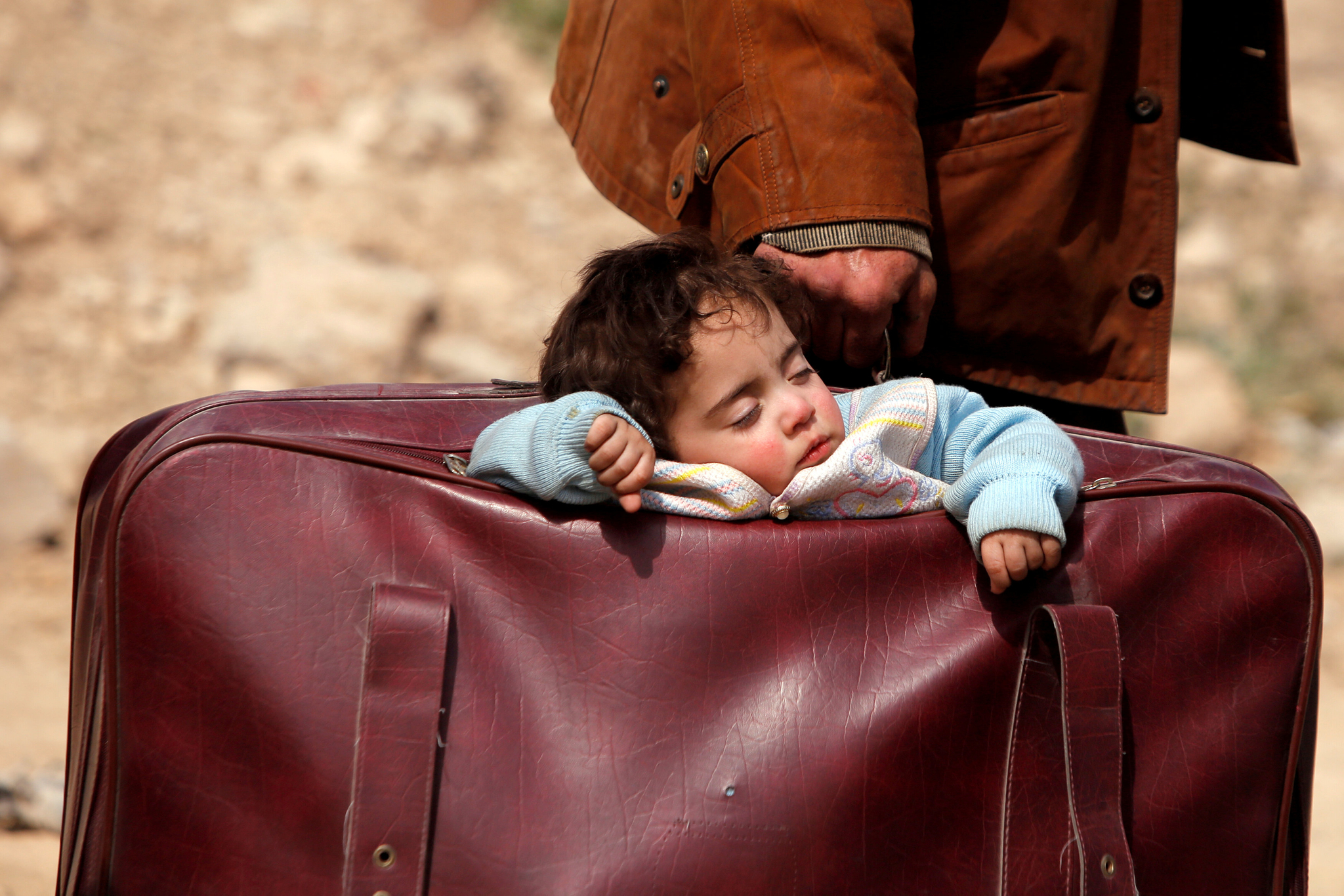 시리아의 동구타 베이트사와 마을에서 촬영된 사진속에 한 아이가 아이의 보호자가 든 가방속에 실려 고된 잠을 자고 있다. 시리아는 7년째 이어진 내전으로 전체 인구 2300만명의 절반인 1200만명이 전쟁 난민이 됐고, 300만명이 목숨을 잃었다. [로이터=연합뉴스]