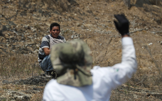 온두라스 이민자 케빈 에스코바르가 22일(현지시간) 멕시코 치아파스 주 피히히아판 외곽에서 단속을 피해 도망가며 이민청 요원을 바라보고 있다. [AP=연합뉴스] 