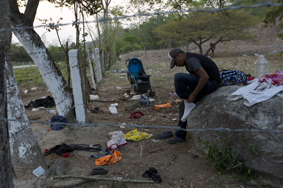 한 이민자가 22일(현지사간) 멕시코 치아파스 주 피히히아판 외곽에서 동료들이 떠난 뒤 양말을 신고 있다. [AP=연합뉴스]