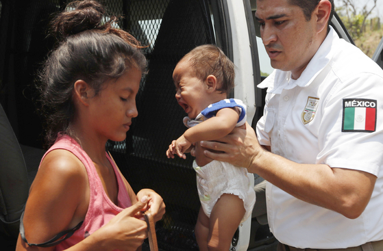  멕시코 이민청 요원이 22일(현지시간) 치아파스 주 피히히아판 외곽에서 체포된 중미 이민자 여성이 짐을 챙길 수 있도록 아이를 안고 있다. [AP=연합뉴스] 