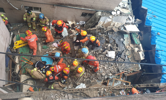 21일 오후 부산 부산진구 부전동 한 2층 단독주택을 떠받치는 기둥이 붕괴해 주택이 무너진 가운데 경찰과 소방대원이 잔해 속에서 숨진 여성을 수습하고 있다. [사진 부산소방본부 ]