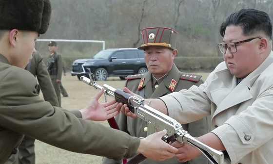 김정은 북한 국무위원장이 서부전선에 위치한 창린도 방어부대를 시찰했다고 조선중앙TV가 25일 보도했다. 사진은 조선중앙TV 화면 캡처로, 김 위원장이 한 부대원에게 총을 건네고 있다. 뒤쪽으로 렉서스 LX570으로 추정되는 SUV 차량도 보인다.[연합뉴스]