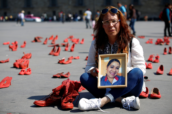 11일(현지시간) 멕시코시티 소칼로 광장에서 열린 여성 폭력 반대 시위에 지난 2017년 남자친구에게 살해된 유제니아 마추카 캄포스의 동생이 언니의 초상사진을 들고있다. [로이터=연합뉴스] 