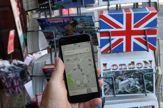 영국 런던에서 우버 사용자가 앱을 통해 차량을 호출하고 있다. 런던시는 지난해 11월 우버에 대한 면서 갱신을 불허했다. 이에 따라 우버 운전자도 직업을 잃게 됐다. [로이터=연합뉴스]