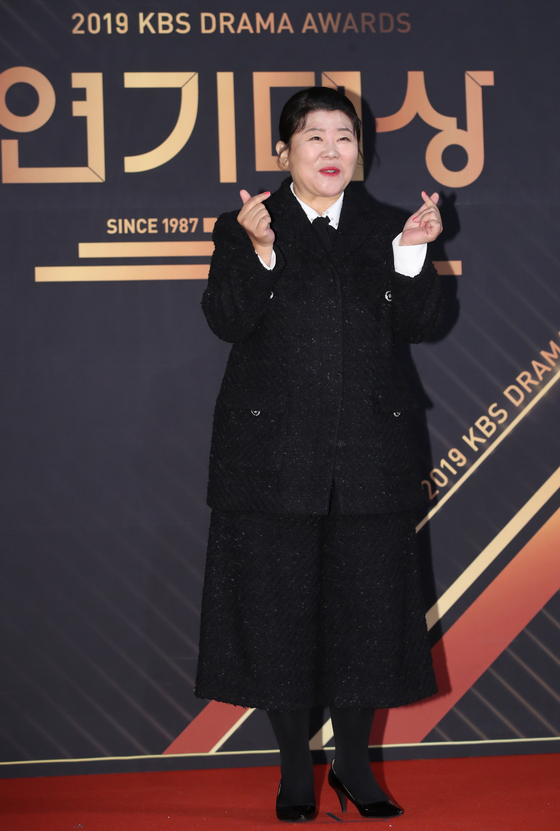 '2019 KBS 연기대상' 레드카펫 행사에 손가락 하트 포즈를 취하고 있는 이정은. 이날 그는 트위트 소재로 만든 재킷과 반바지를 입어 귀여운 매니시 룩을 보여줬다. [사진 뉴스1]