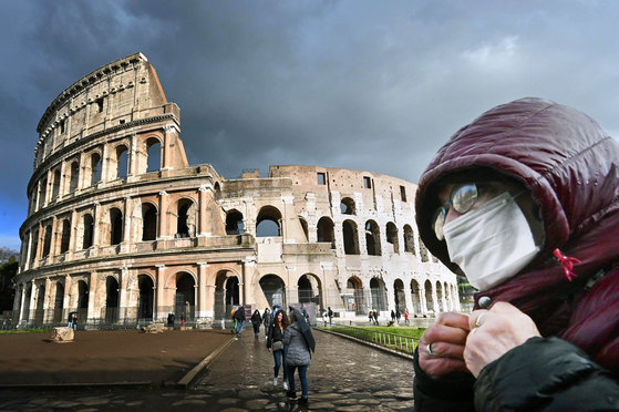 지난 7일 이탈리아 로마의 콜로세움 앞에서 한 관광객이 마스크를 쓴 채 옷깃을 여미고 있다. [AFP=연합뉴스]