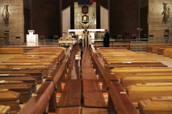 이탈리아 세리아테의 산 주세페 교회에서 한 사제가 신종 코로나바이러스 감염증으로 숨진 사람들의 관을 모아두고 기도를 올리고 있다.[AP 연합뉴스] 