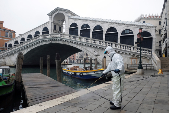 지난 3월 13일 관광객이 끊긴 이탈리아 베니스 리알토 다리 인근에서 보호복을 입은 공무원이 방역작업을 하고 있다. [로이터=연합뉴스]