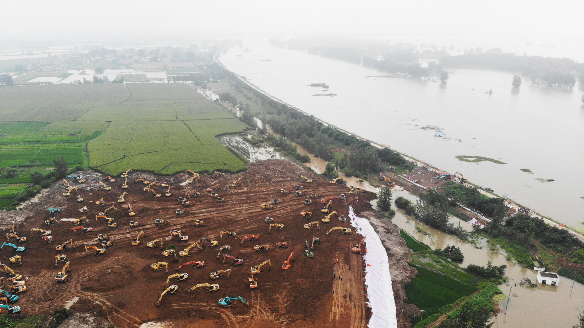  28일(현지시간) 중국 안후이성 인근 잉샹현의 다자이 호에서 폭우로 인해 제방이 일부 훼손되어 범람이 발생하자 수십여대의 중장비를 동원해 임시 제방을 쌓고 있다. [신화=연합뉴스]