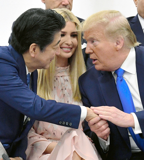아베 신조 일본 총리와 도널드 트럼프 미국 대통령이 지난해 6 월 29 일 일본 오사카에서 열린 G20 정상 회의에서 트럼프 대통령의 딸 이반카를두고 손을 잡고 대화를 나누고있다. [교도=연합뉴스]