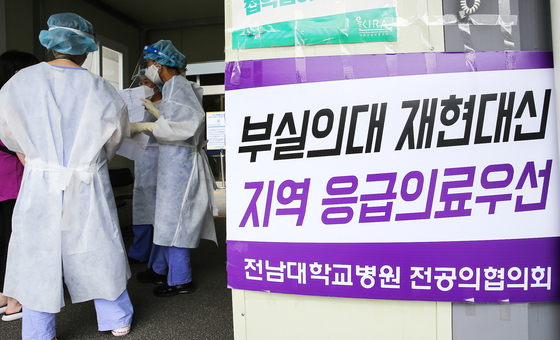 On the morning of the 31st, nurses check patients' temperatures in front of the emergency room at Chonnam National University Hospital.  On the wall, there is a sign that says the main council of the university: 