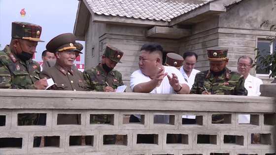 President Kim looks back at the rebuilt Daecheong-ri house.  Holding a cigarette, leaning against the wall, talking. [연합뉴스] 