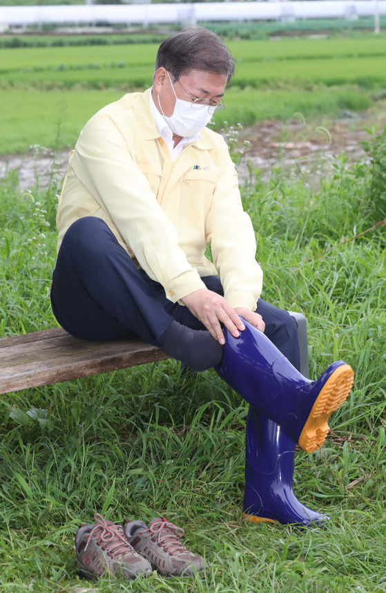 On the 12th, President Moon Jae-in visits the area affected by the torrential downpour, Cheonan, and changes his shoes with agricultural boots. [청와대사진기자단]