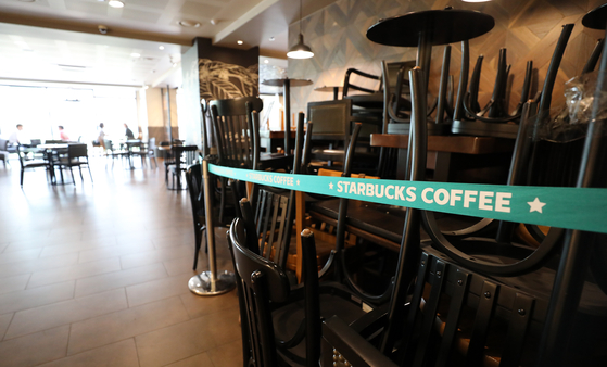 Chairs and tables are stacked in a corner of a Starbucks store in Seoul.  News 1 