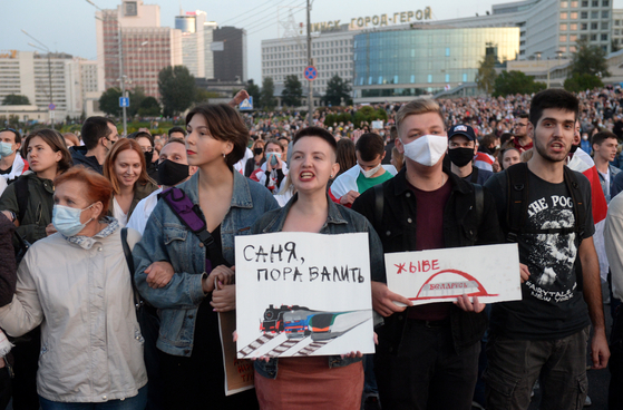 The scene of the Minsk assembly in Belarus on this day.  A participant in the demonstration holds a sign that reads: 