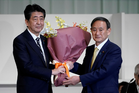 Japanese Prime Minister Yoshihide Suga (right) presents flowers to former Prime Minister Shinzo Abe, who will retire on the 16th. [로이터=연합뉴스]