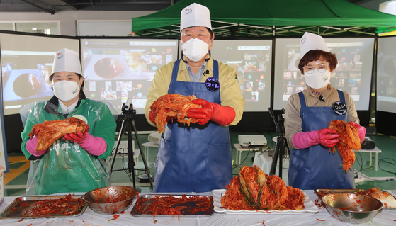 On the 24th, a `` non-face-to-face kimchi-making event '' was held in the parking lot of the Dongnae Safety Dream Center in Dongnae-gu, Busan, and Kim Woo-ryong, Dongnae-gu's director and chief from the Saemaul Women's Association in Dongnae-gu, Dongnae-gu (left), are making kimchi.  The event was held in such a way that the Dongnae-gu Office Security Dream Center event site and volunteers who participated online connected with videos and put kimchi in different places.  Reporter Song Bong-geun