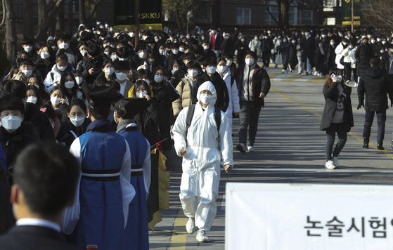 An examinee wearing a full-length quarantine uniform and taking a writing test at Sungkyunkwan University is walking out the front door.  Reporter Kim Seong-ryong