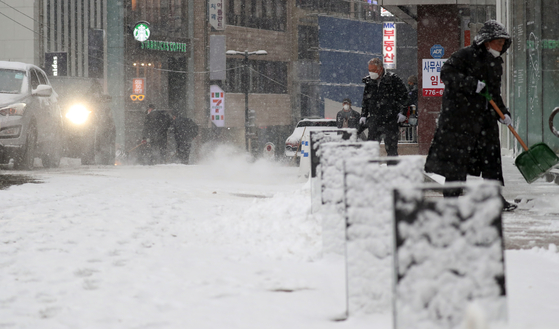 On the afternoon of the 12th, after heavy snowfall, citizens are clearing the snow on the streets of Myeongdong, Seoul.  News 1