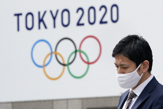 한 남성이 일본 도쿄도 청사 앞에 걸린 도쿄올림픽 광고판을 지나고 있다. EPA=연합뉴스