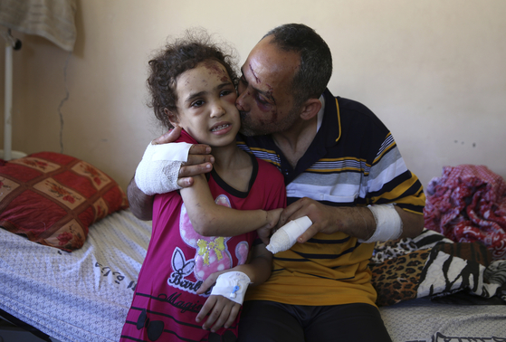18일 이스라엘군의 가자지구 공습으로 다섯 명의 자녀 중 네 아이를 잃은 라이어드 이시콘타나(42)가 자녀 중 유일한 생존자인 수지 이시콘타나를 안고 AP통신과 인터뷰를 하고 있다.[AP통신=연합뉴스]
