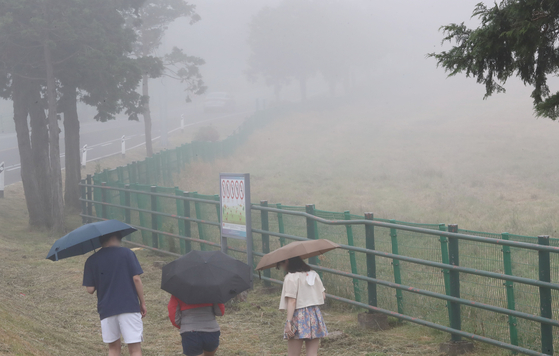 전국 동시 장마를 앞둔 2일 오후 제주시 용강동 마방목지에서 관광객들이 우산을 쓰고 걷고 있다. 뉴스1