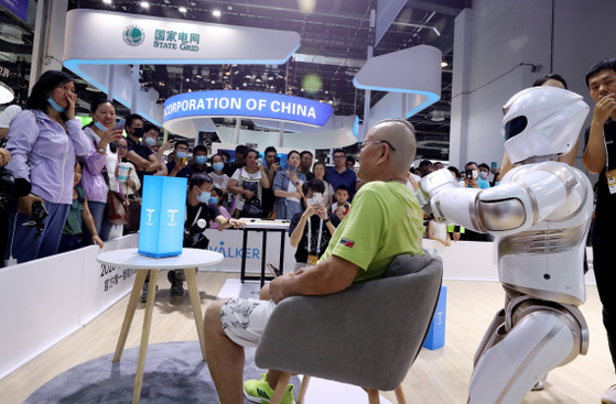 한 관람객이 8일 '2021 세계인공지능대회'에서 휴머노이드 로봇이 해주는 마사지를 받고 있다. ⓒ신화통신