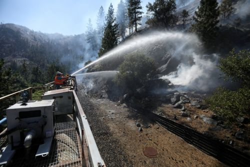 지난 17일(현지시간) 미국 캘리포니아주 플루마스 국유림에서 소방관들이 기차 선로를 보호하기 위해 물을 뿌리고 있다. [로이터=뉴스1]